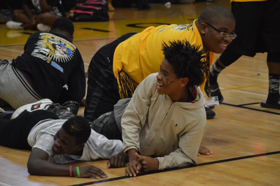 JV football players Brysom Jones, freshman, Kyron Bailey, freshman, and Jonathan York, sophmore, fall to the floor after going up against the varsity football team in a tug-of-war competetion. “It was funny because it was our first time going against varsity,” said Bailey. “We knew we were going to lose because they’re strong.”  