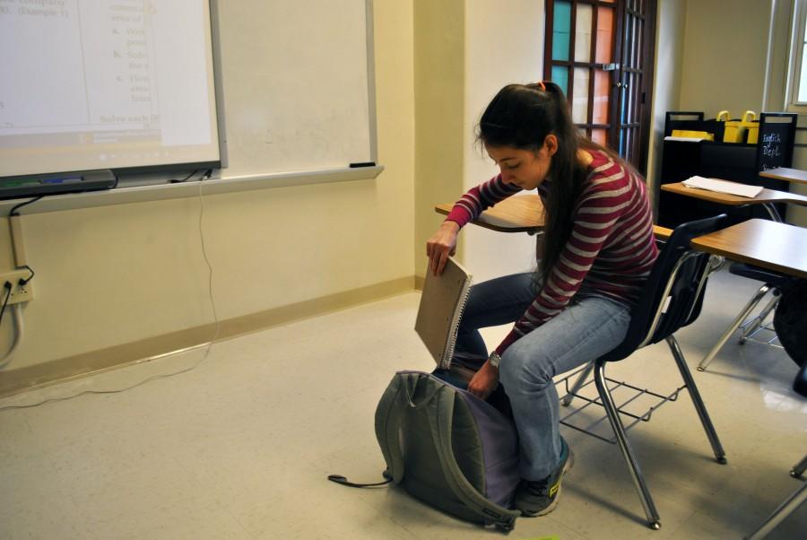 While sitting in Mr.Cloud room Lydia Soifer, senior, attempts to put her journal in her backpack after using her lunch period to get ahead in school work. “It would be nice if it was light but it’s definitely useful to have even though it’s heavy,” said Soifer. PHOTO BY JACELYNN ALLEN