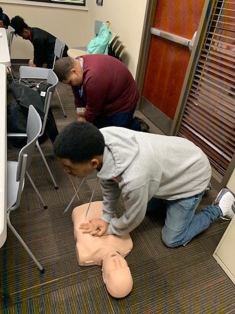  At their first session, Christian Hollloway and Timothy Dailey, seniors, perform CPR on a dummy as part of their physical test to complete their CPR certification. “So far it’s been super exciting just based on the things we’ve been told we will do and the responsibility we will have,” Dailey said.