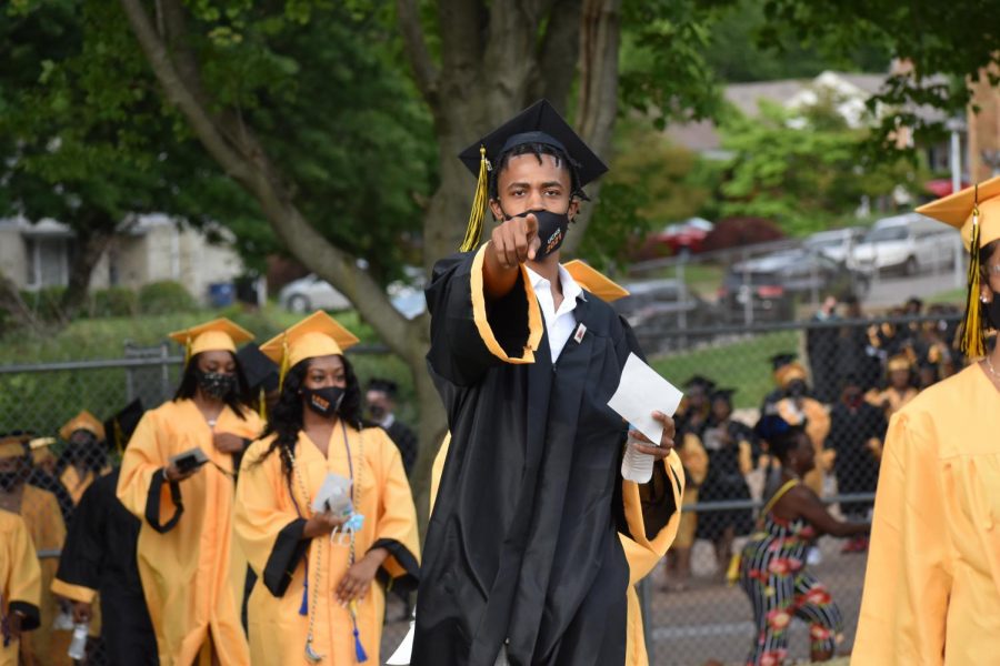 Brandon Ming, points at camera while walking up into graduation 