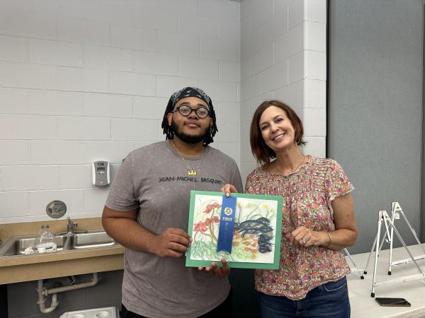 Mondis Doyle, senior, poses alongside Marnie Claunch, art teacher, as he shows off his first place. I did not think I was going to win, Doyle said. I had no idea how to react; I was happy.